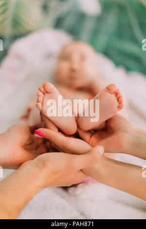 The vertical close-up view of the toddle feet held by the parents` hands. Stock Photo